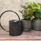 Black indoor watering can with thin round handle and curved spout next to two grey plant pots - Quality Garden Supplies